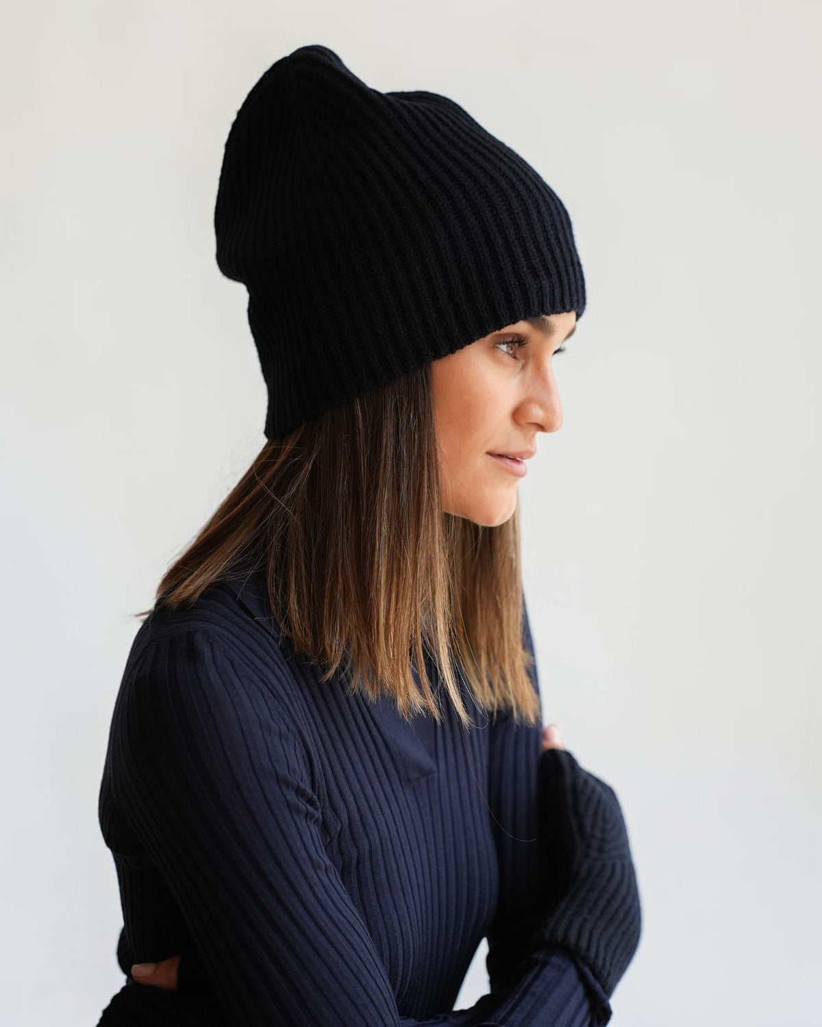 Seitenansicht der Allude Rippstrick-Mütze in Dunkelblau aus Cashmere am Model