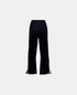 Navy knitted pants, front view with a wide waistband, white hem trim and side slits.