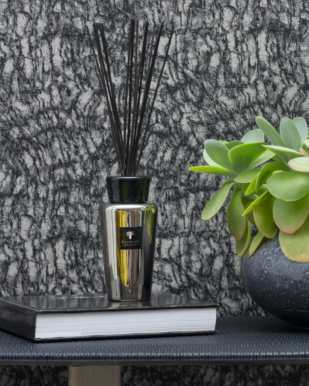 Baobab Collection Raumduft-Diffuser Les Exclusives Platinum 500 ml auf Büchern neben einer grünen Pflanze im Interieur