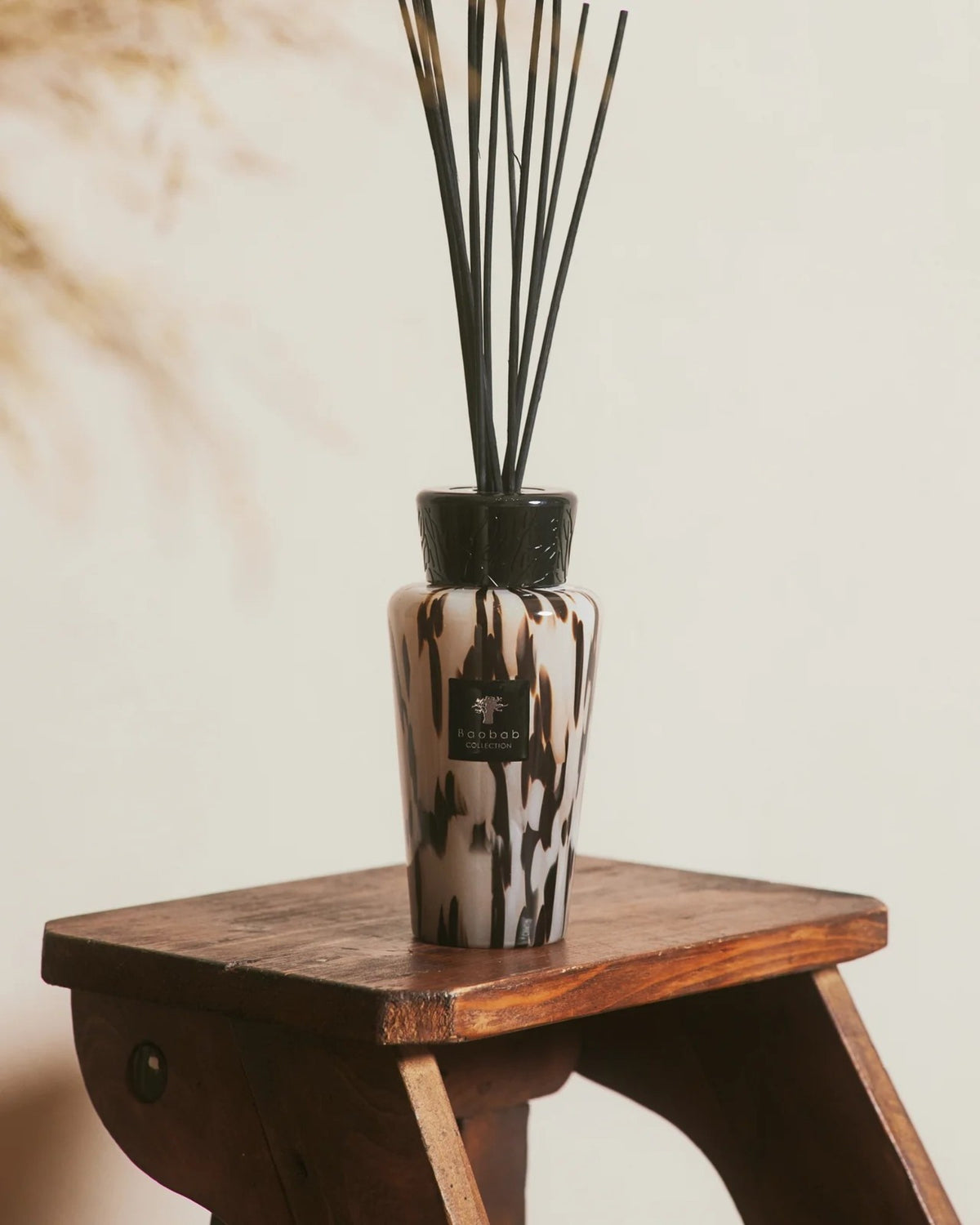 Baobab Collection Raumduft-Diffuser Pearls Black 500 ml auf einem Holzhocker im Interieur