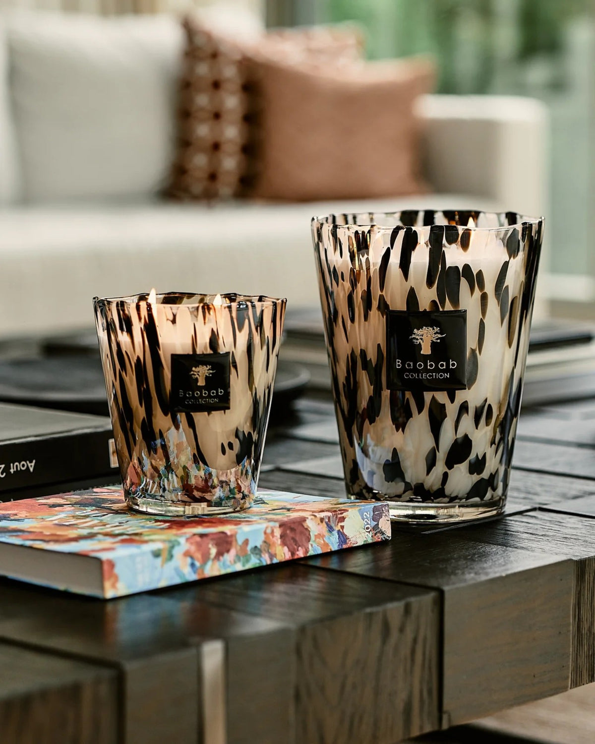 Zwei Baobab Collection Duftkerzen Pearls Black in unterschiedlichen Größen auf einem Couchtisch