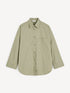 Olive-green oversized shirt with a chest pocket and curved hem, front view.