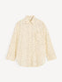 Cream button-down shirt with black polka dots and a curved hem, front view.