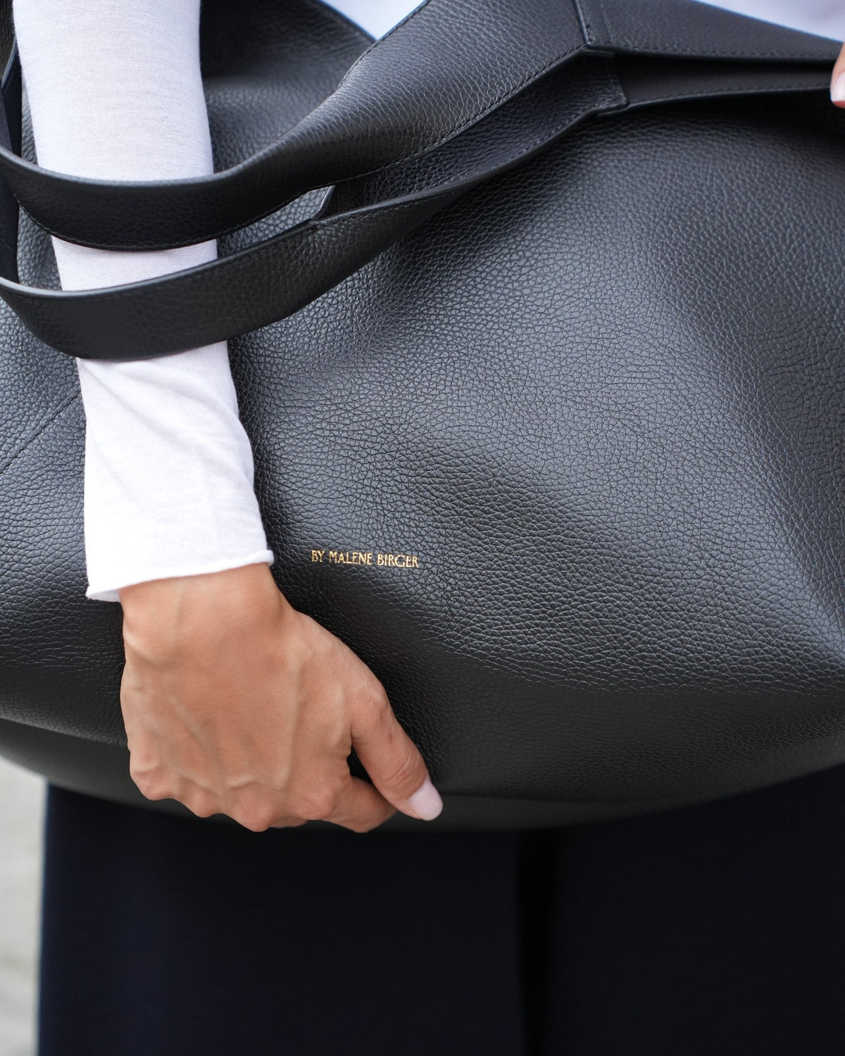 Detail der Lederstruktur der großen schwarzen Tote Bag von By Malene Birger am Model