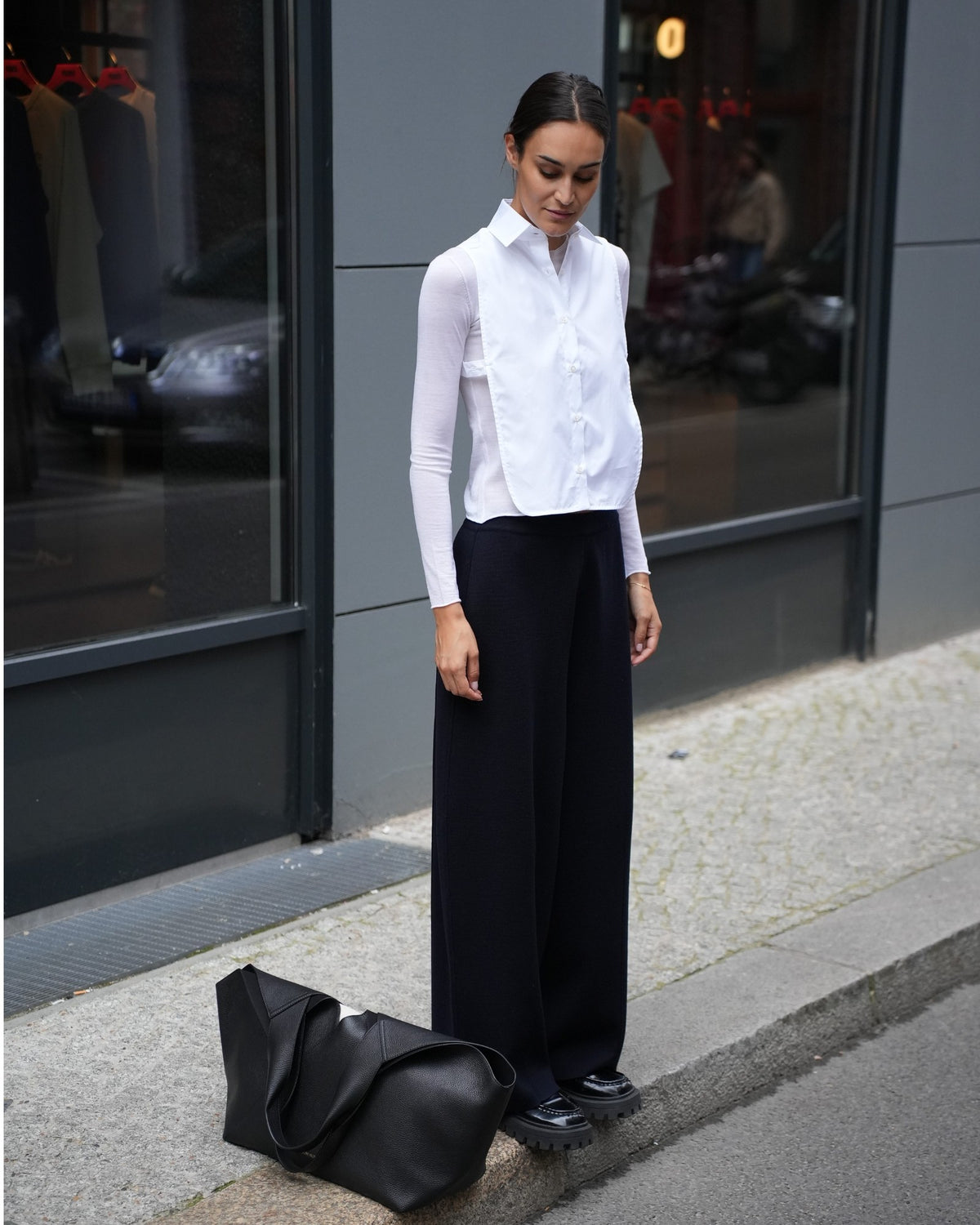 By Malene Birger große Tote Bag aus schwarzem Leder neben dem Model auf dem Boden