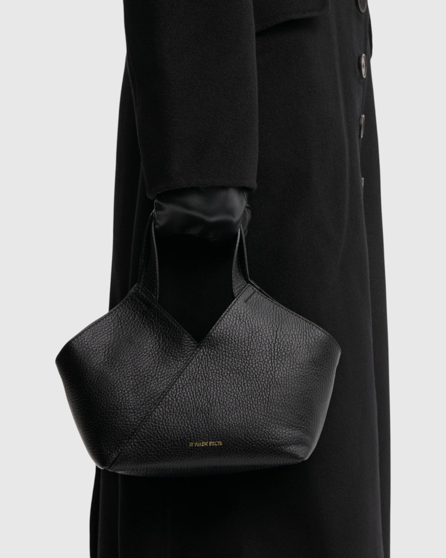 By Malene Birger kleine schwarze Ledertasche mit breiten Henkeln seitlich am Model getragen