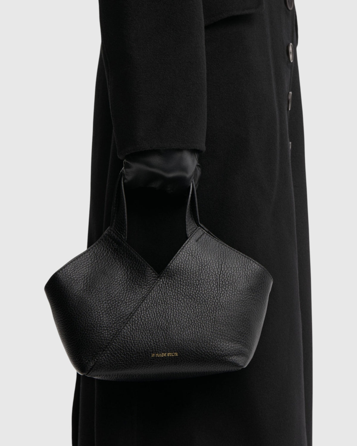 By Malene Birger kleine schwarze Ledertasche mit breiten Henkeln seitlich am Model getragen