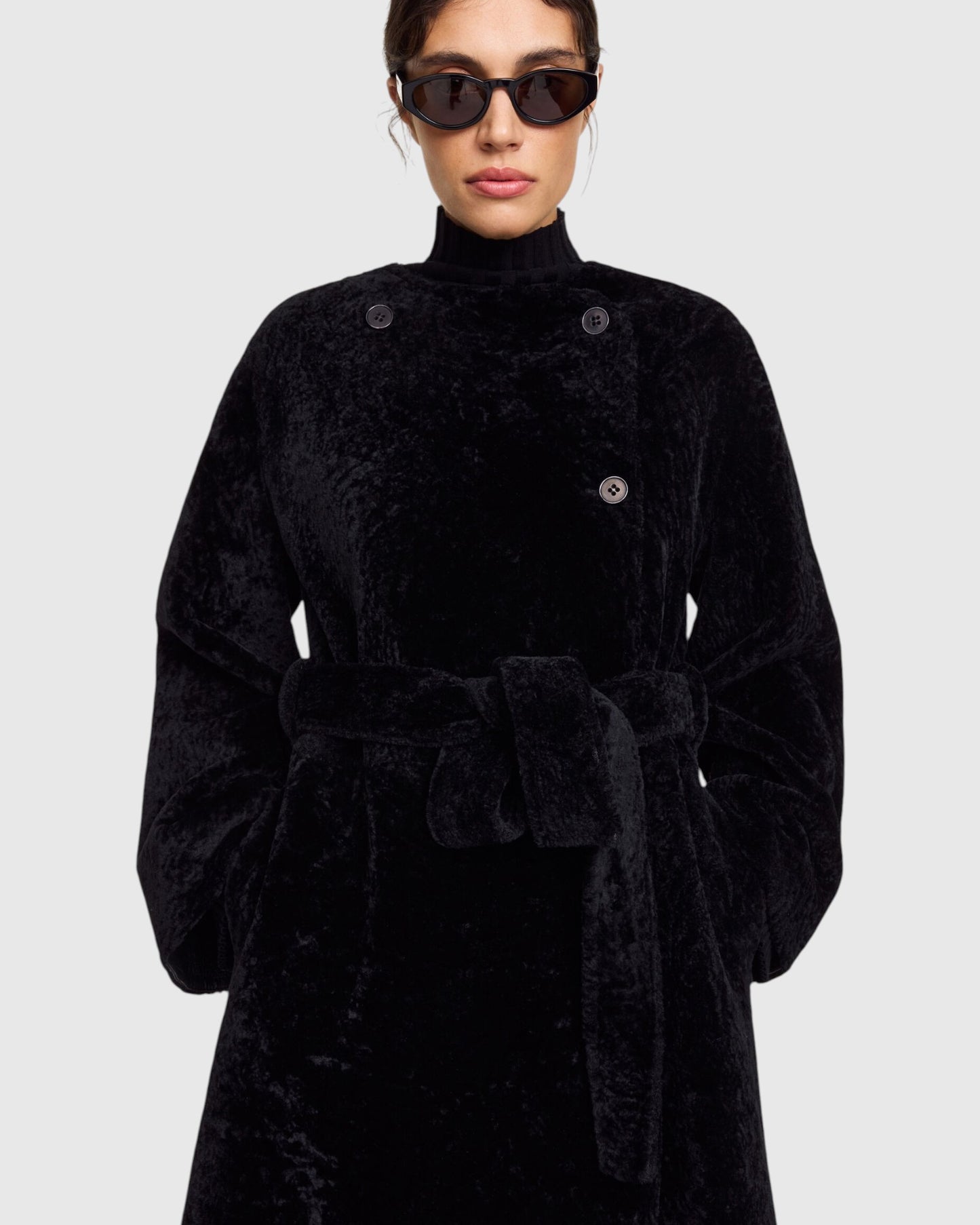 Detail des By Malene Birger reversiblen Pelzmantels in Schwarz getragen