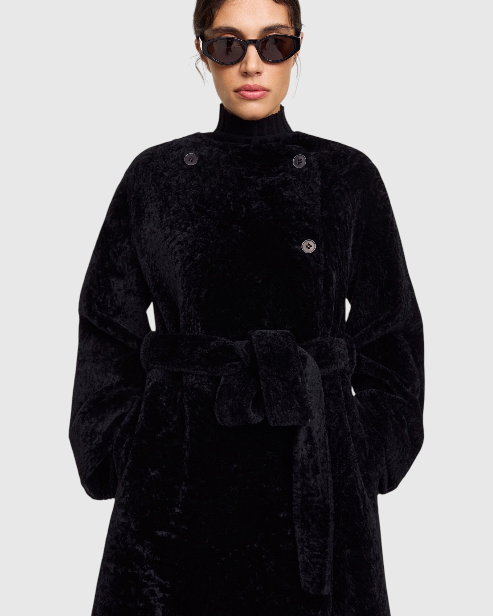 Detail des By Malene Birger reversiblen Pelzmantels in Schwarz getragen