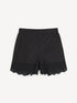 Black cotton shorts, front view with scalloped broderie anglaise hems.