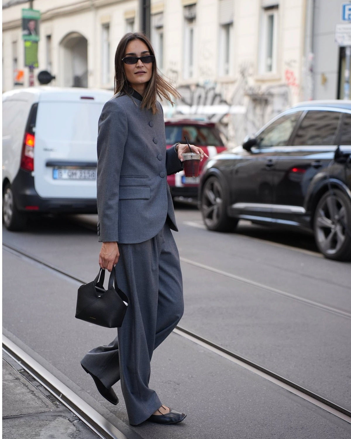Model walking in the dark grey Claye blazer by By Malene Birger, three-quarter view.