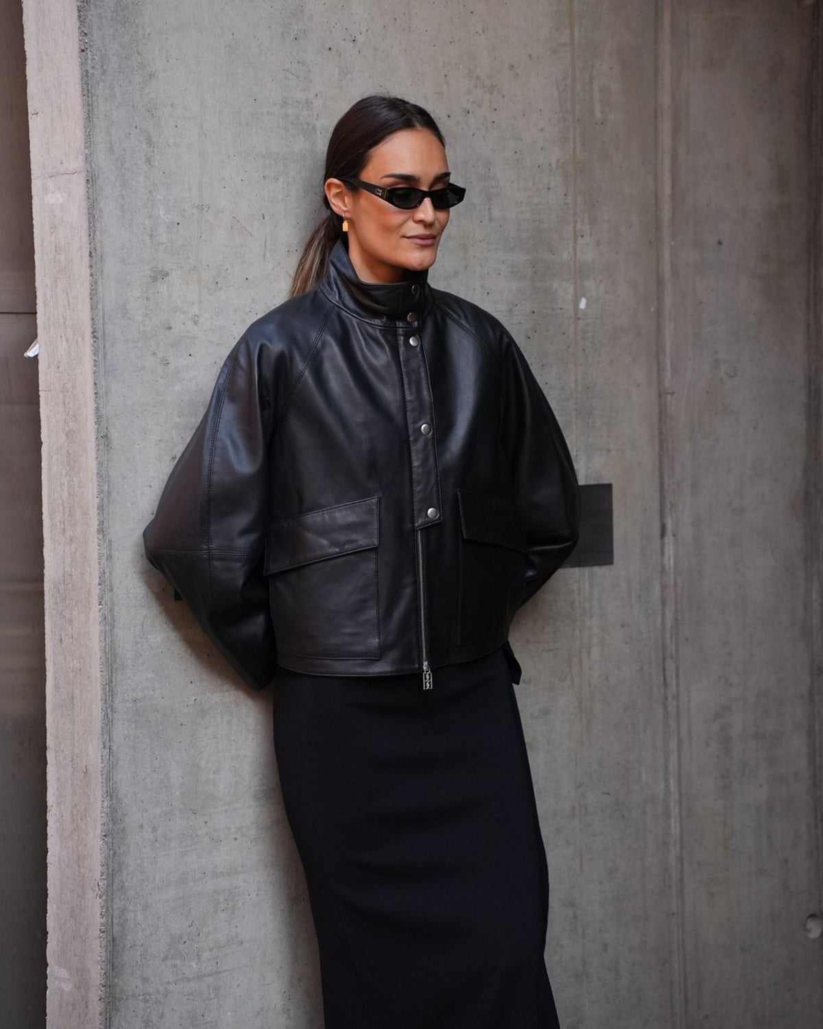 By Malene Birger Suzanne Lederjacke in Schwarz am Model von vorne mit Stehkragen und Pattentaschen, kombiniert mit schwarzem Rock