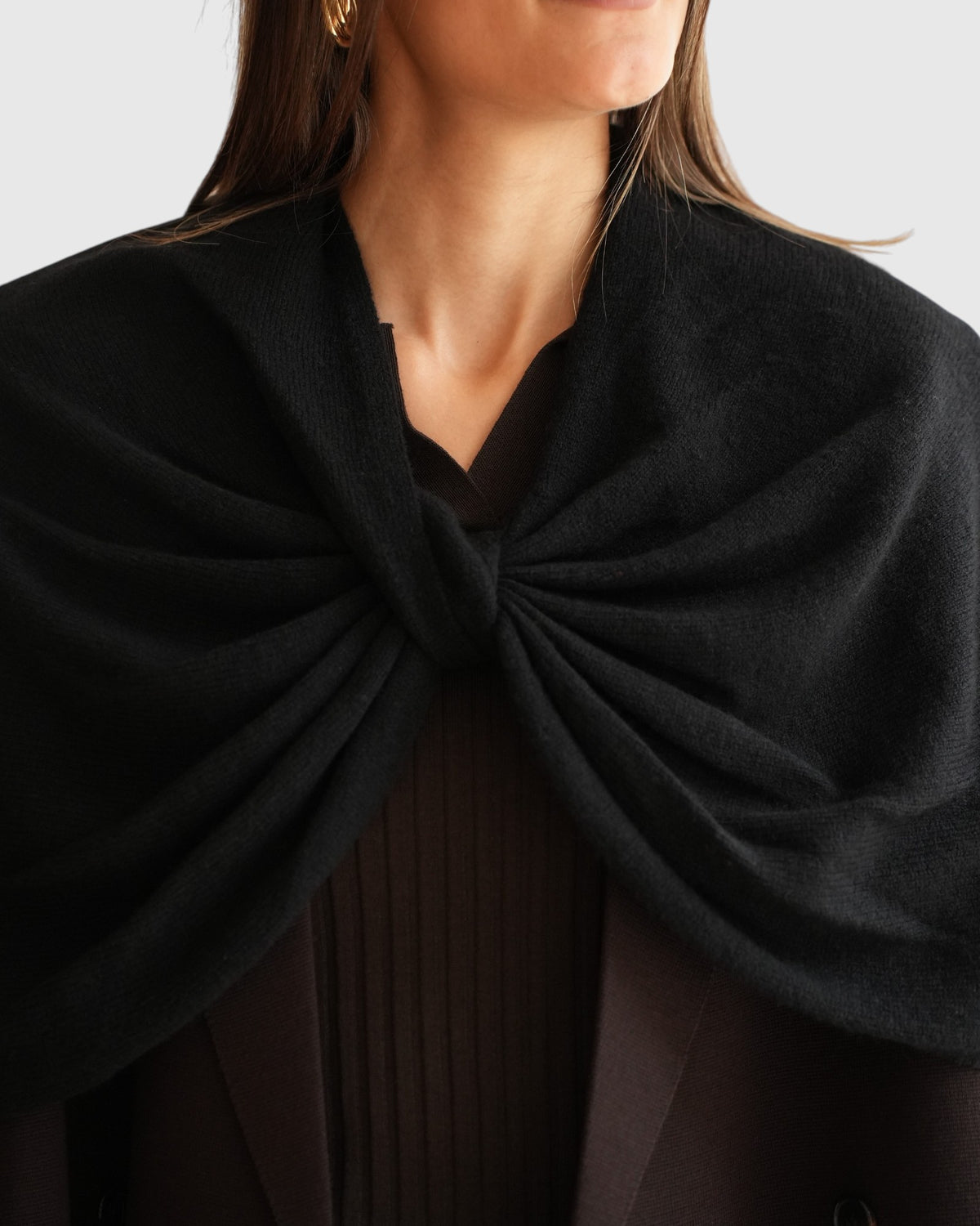 Knotendetail des schwarzen By Malene Birger Wollcapes von vorne am Model