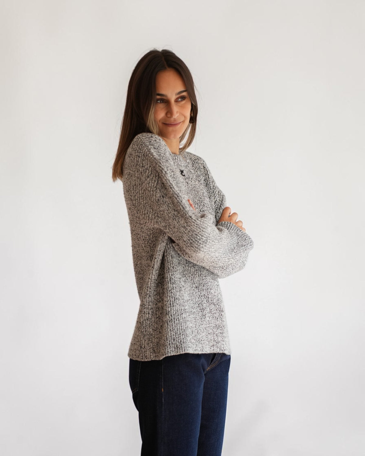 Black and white melange Courrèges sweater on a model with folded arms, showing the relaxed silhouette