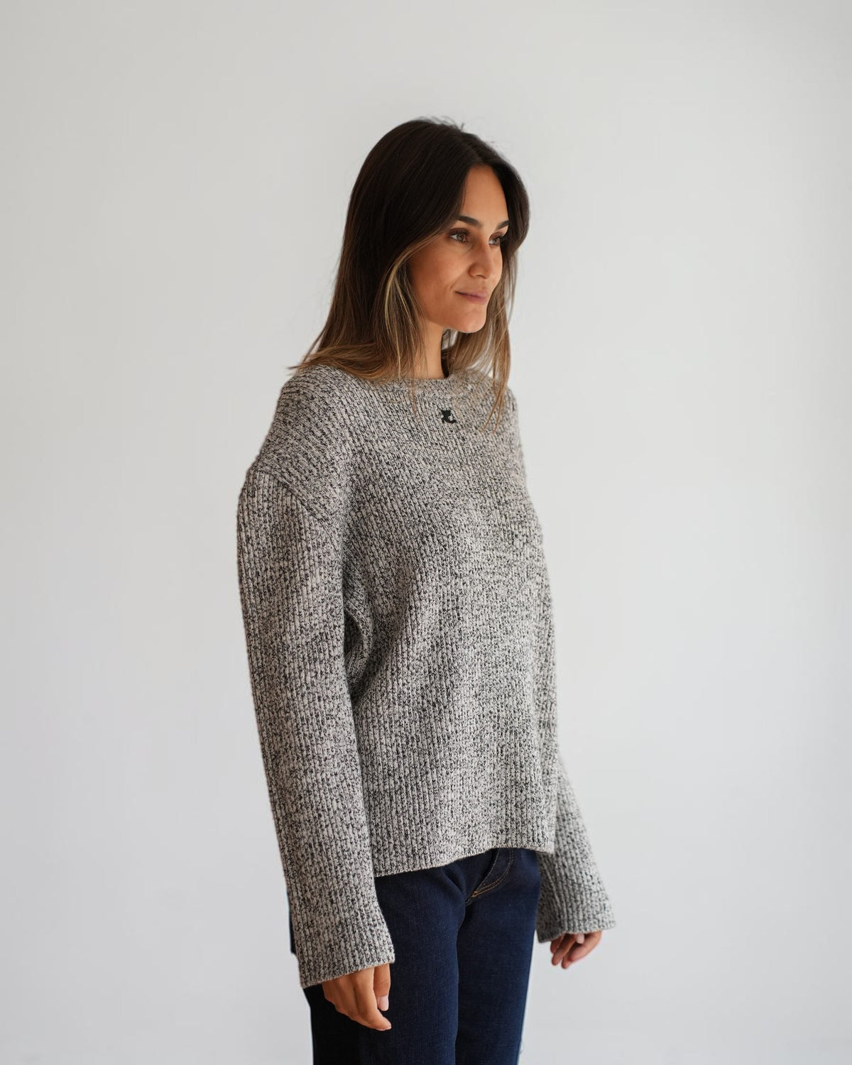 Black and white melange Courrèges sweater on a model in three-quarter view, showing the wide sleeves