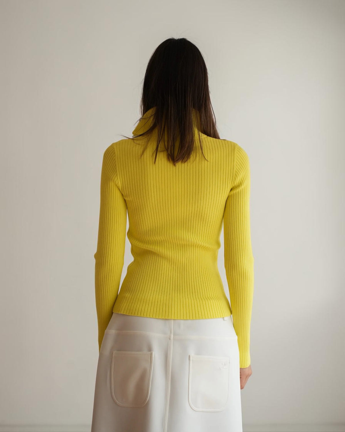 Gelber Rippstrick-Pullover mit langen Ärmeln und körpernaher Passform, Rückansicht am Model.