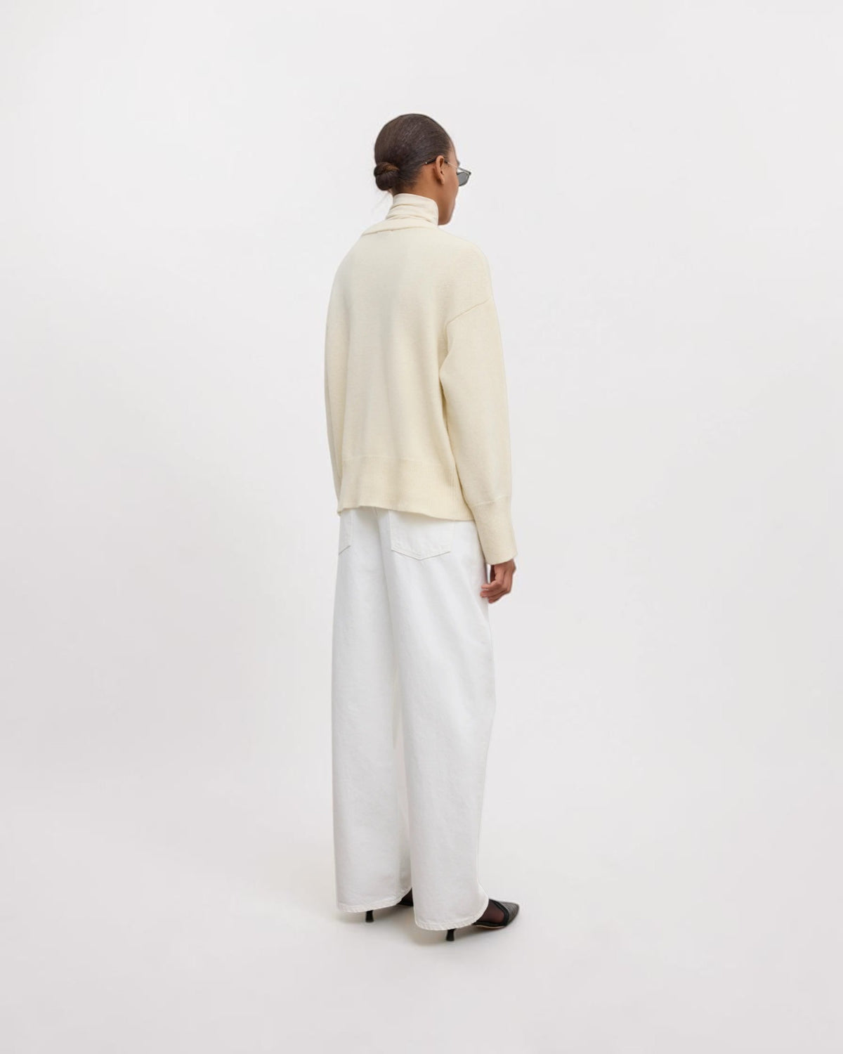 Model trägt cremeweißen Oversized-Wollpullover in Rückansicht