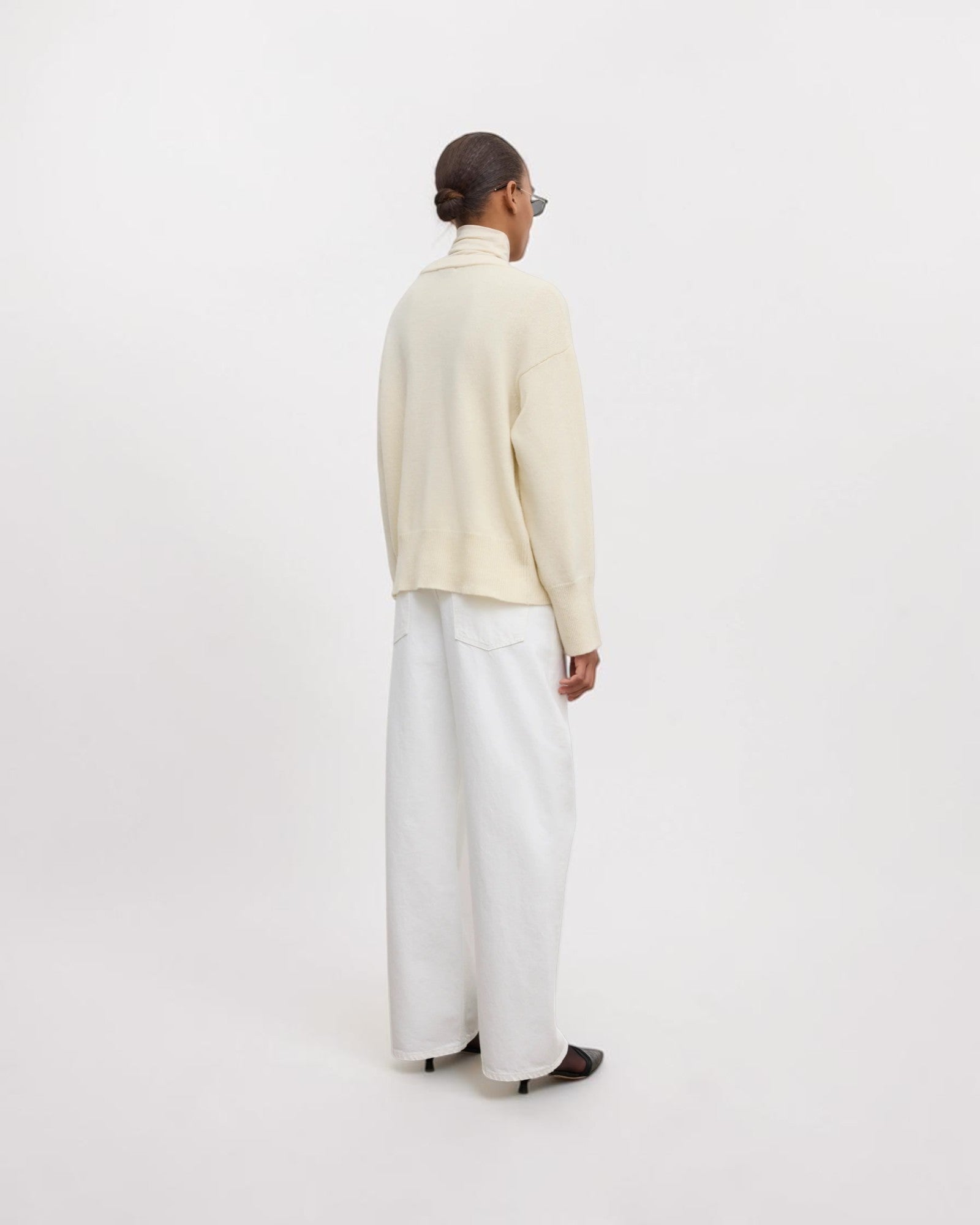 Model trägt cremeweißen Oversized-Wollpullover in Rückansicht