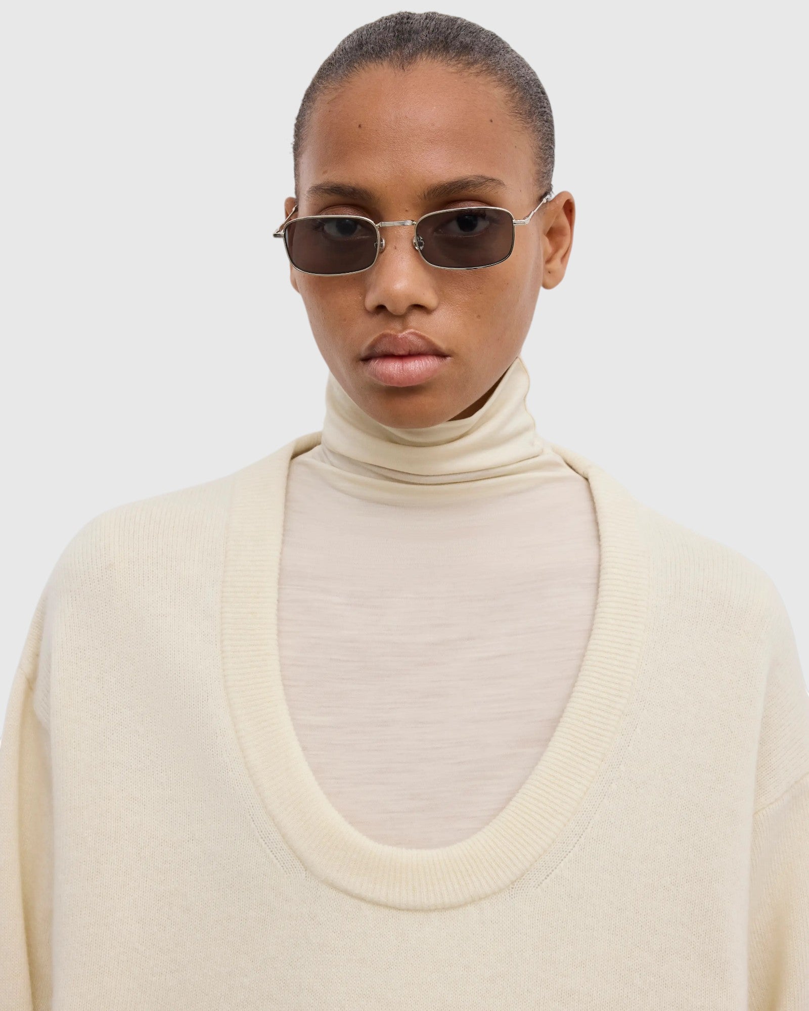 Detail des tiefen Rundhalsausschnitts am cremeweißen Wollpullover