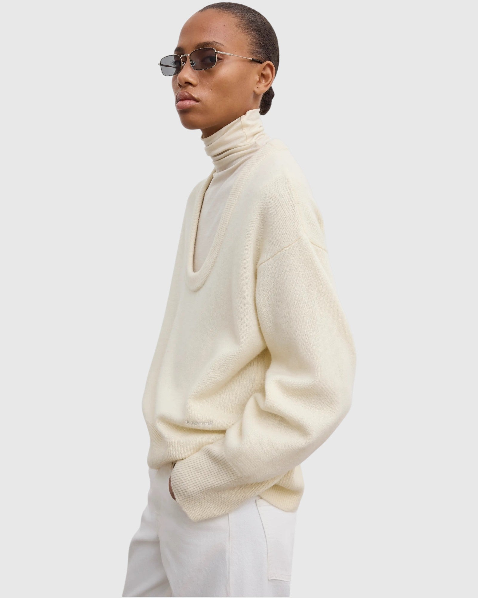 Model trägt cremeweißen Oversized-Wollpullover in Seitenansicht