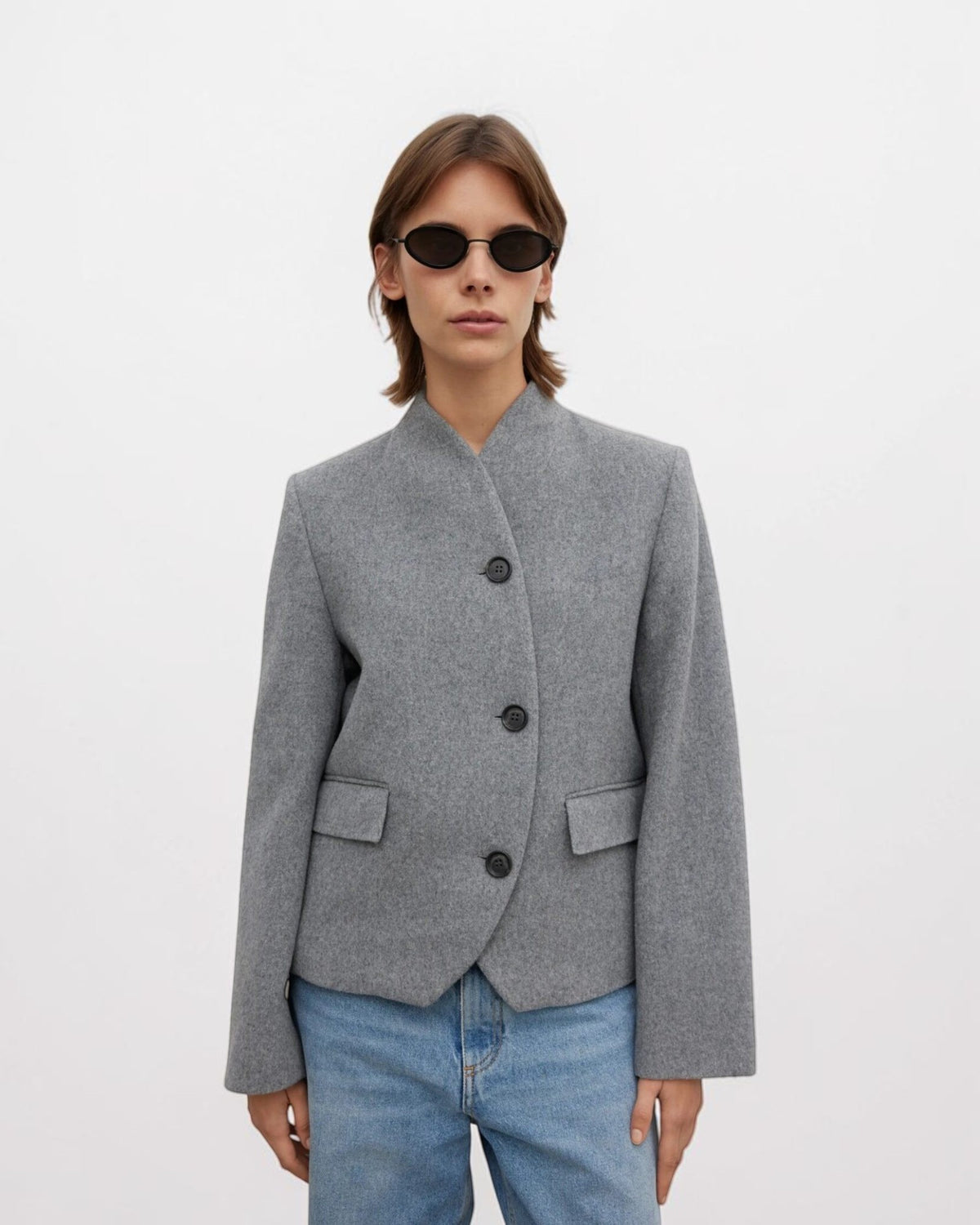 Stehkragen, dunkle Knöpfe und Pattentaschen der grauen House of Dagmar Wolljacke am Model von vorne