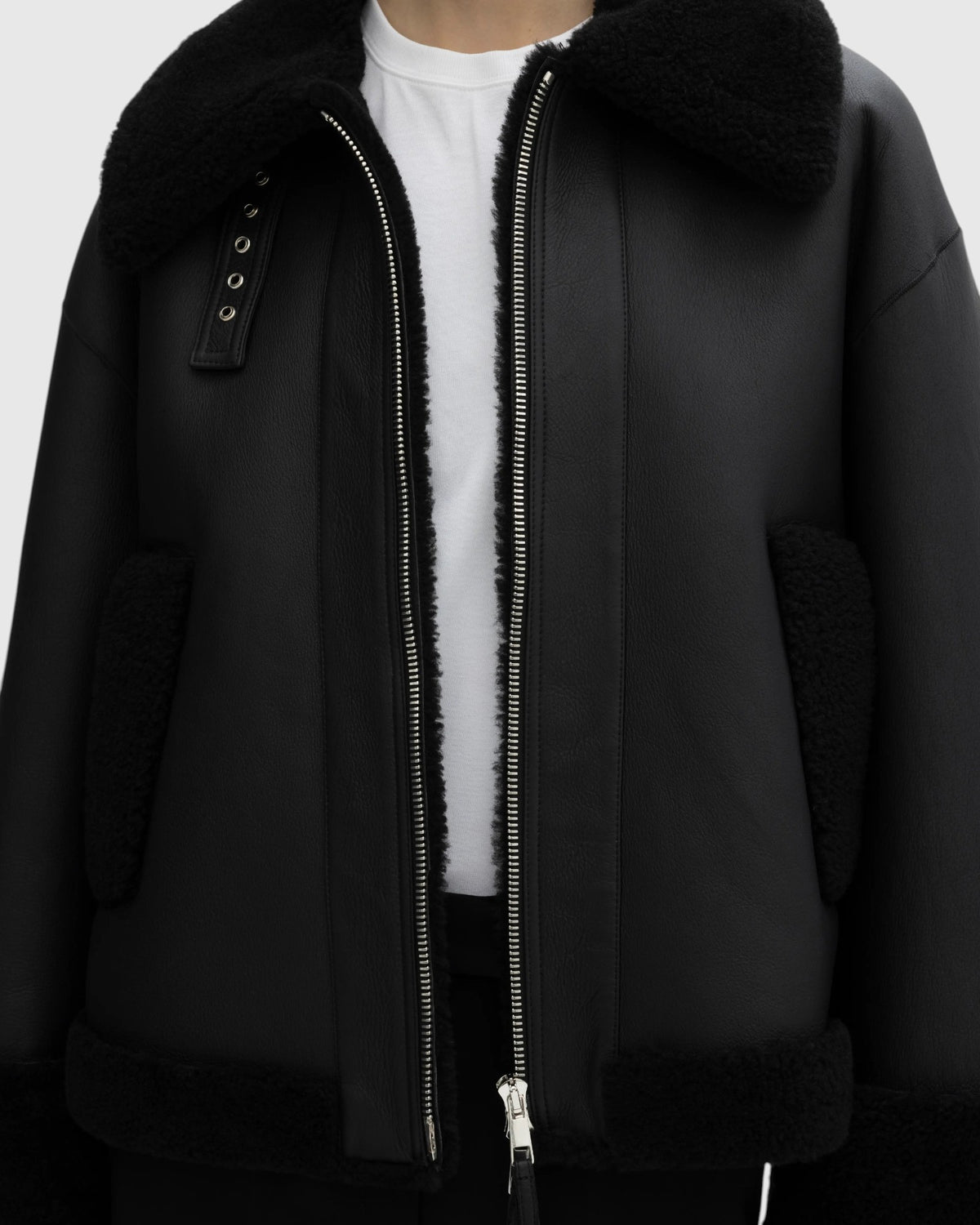 House of Dagmar schwarze Lammfelljacke offen am Model mit Fellkragen und Taschenbesätzen in der Nahaufnahme