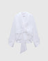 White draped poplin blouse with a shawl collar and oversized front bow, front view.