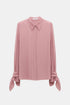 Pink blouse with a pointed collar, concealed button placket and ties at the cuffs, front view.