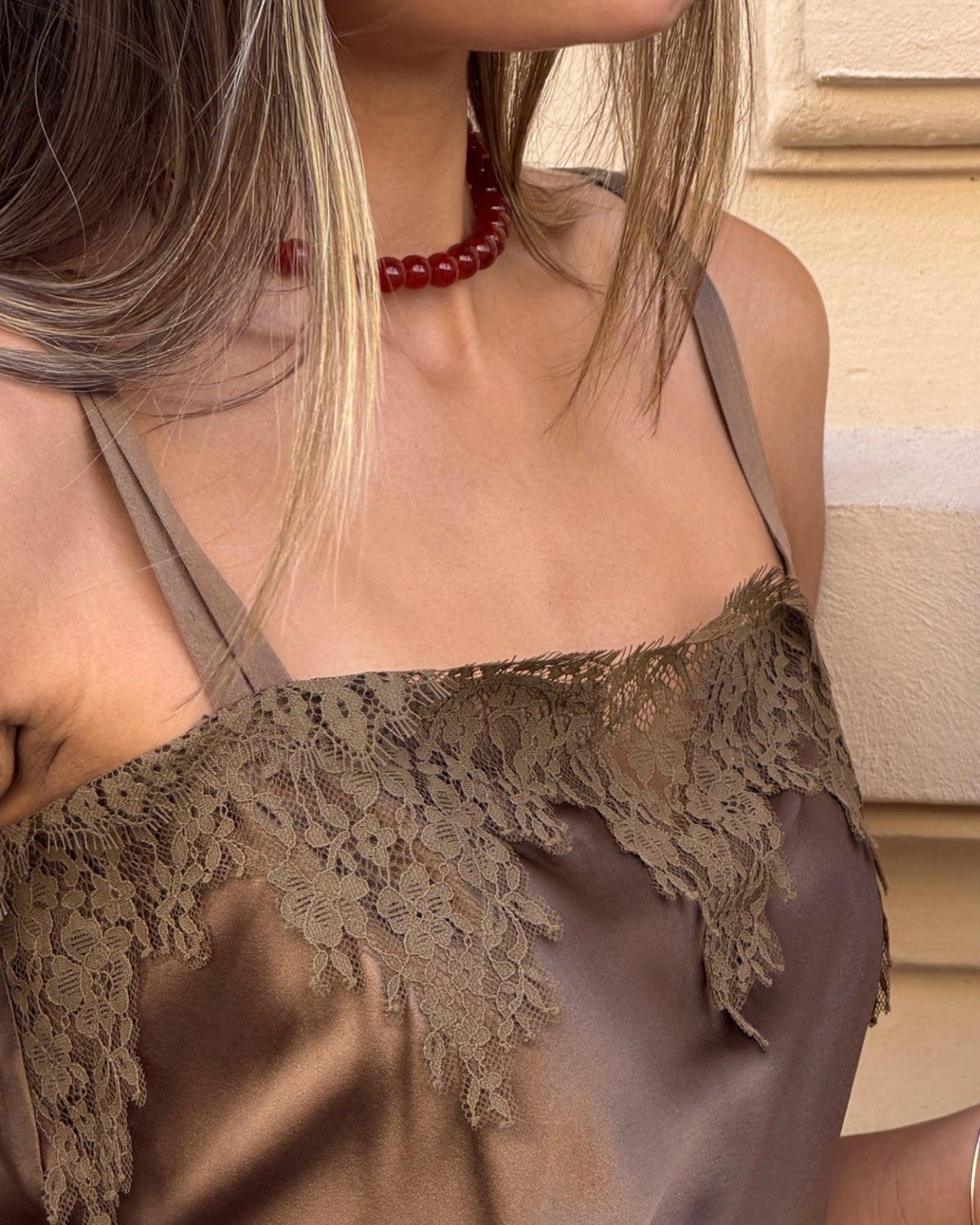 Brown Dorothee Schumacher silk top on a model, close-up of the lace trim at the neckline.