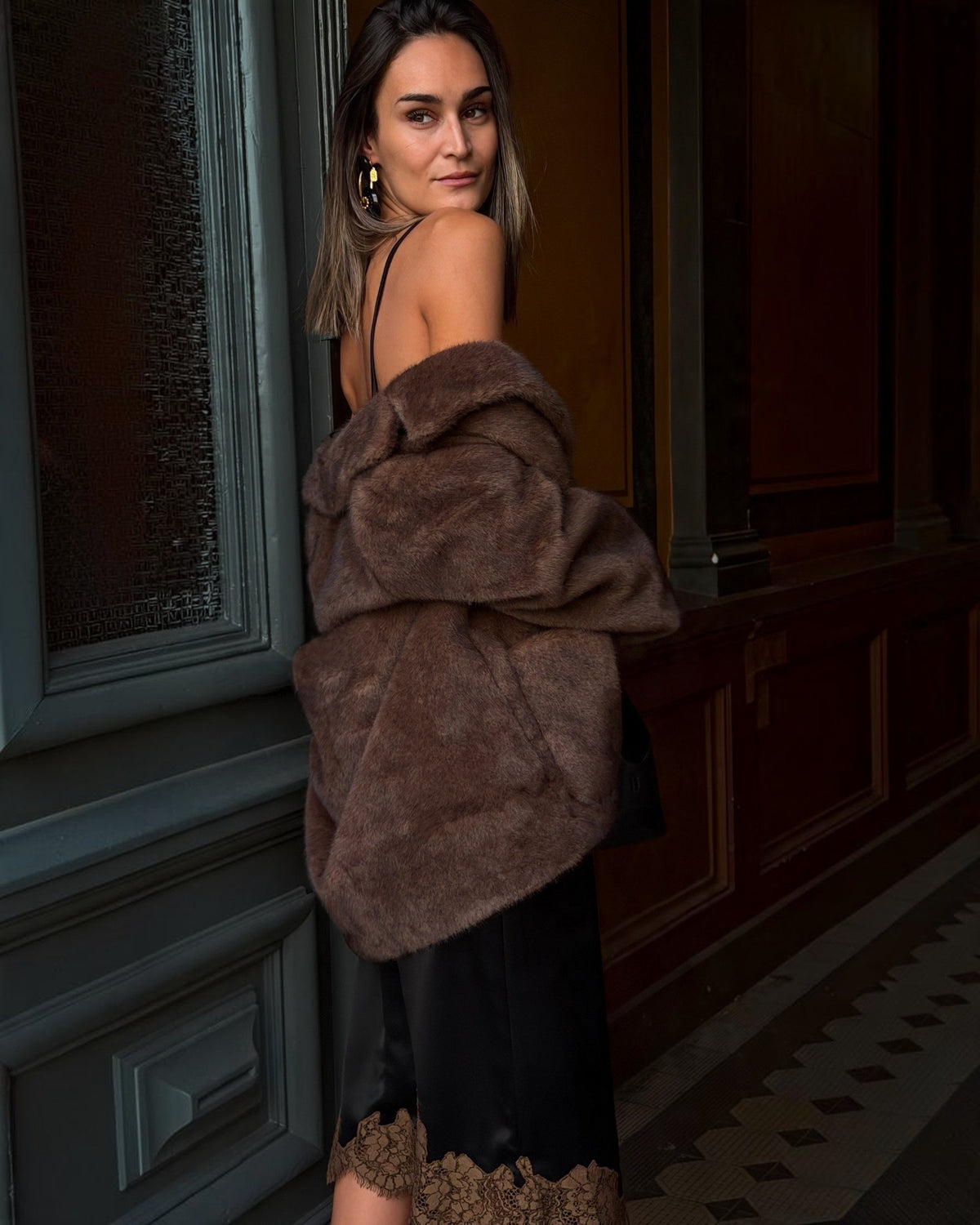 Braune Faux-Fur Jacke von Dorothee Schumacher locker über den Armen eines Models mit Blick über die Schulter.