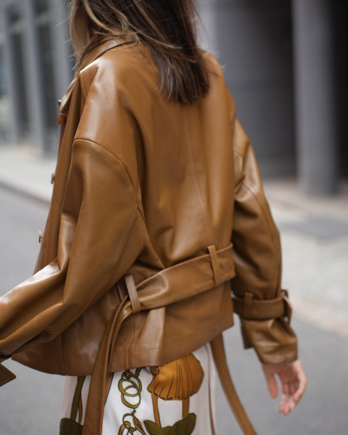 Saffron Dorothee Schumacher leather jacket with a waist belt on a model, rear three-quarter view.