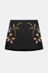 Black A-line mini skirt with pink and lilac floral motifs, front view.