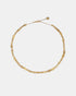Short gold-tone necklace with alternating sculpted beads, decorative spacers and an extension chain, laid flat.