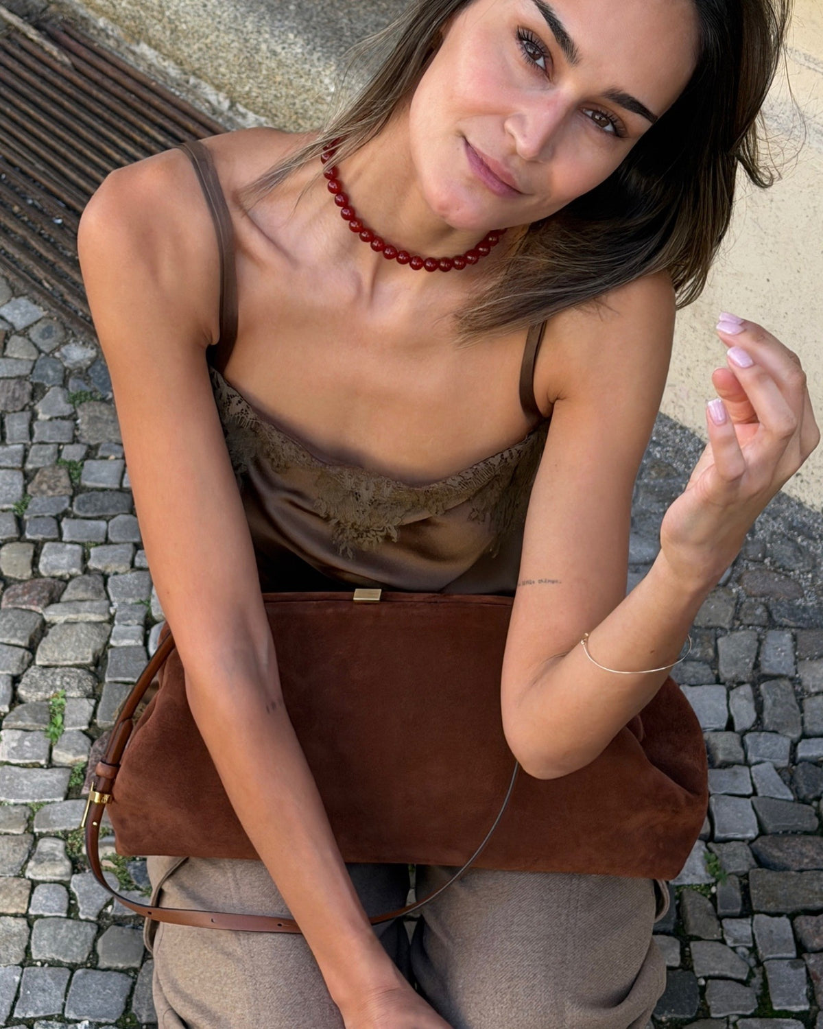 Red Mary necklace by Lié Studio worn by a seated model, viewed at an angle from above.