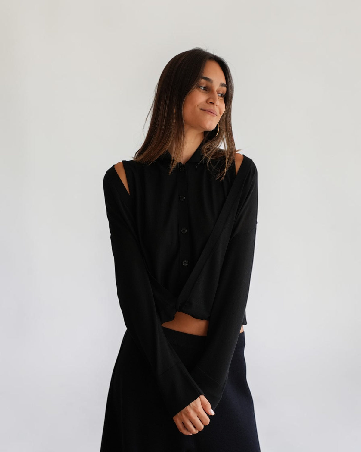 Schwarzer Polo-Cardigan von MRZ mit fließender Vorderseite am Model mit gefalteten Händen