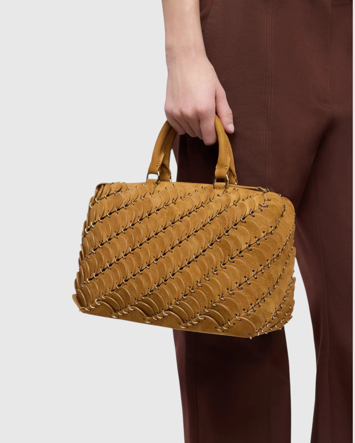Rabanne Boston-Tasche in Camel mit kurzen Henkeln in der Hand des Models in Nahansicht