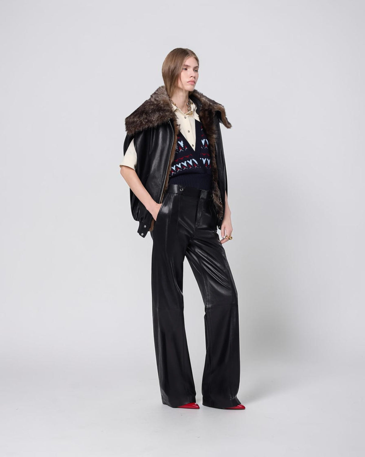 Rabanne Leder-Cape in Schwarz mit Lammfellkragen am Model in seitlicher Dreiviertelansicht