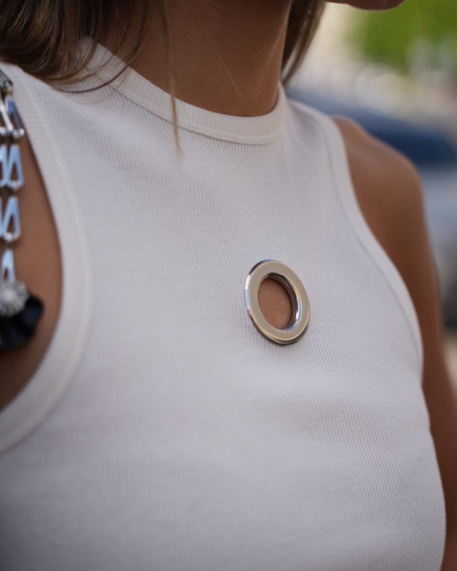 Detail des weißen Rabanne Tops mit silberfarbenem Ring