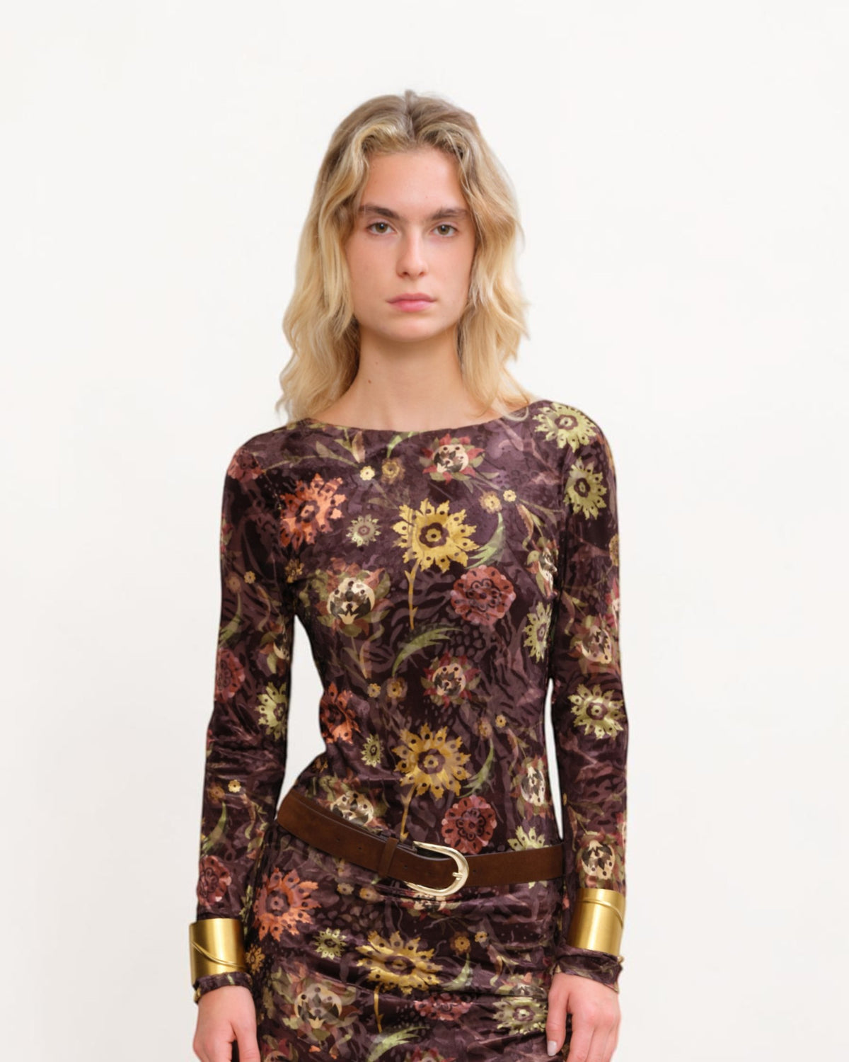 Close-up of Siedrés Alin velvet dress on the model with yellow and rust-coloured flowers on dark brown