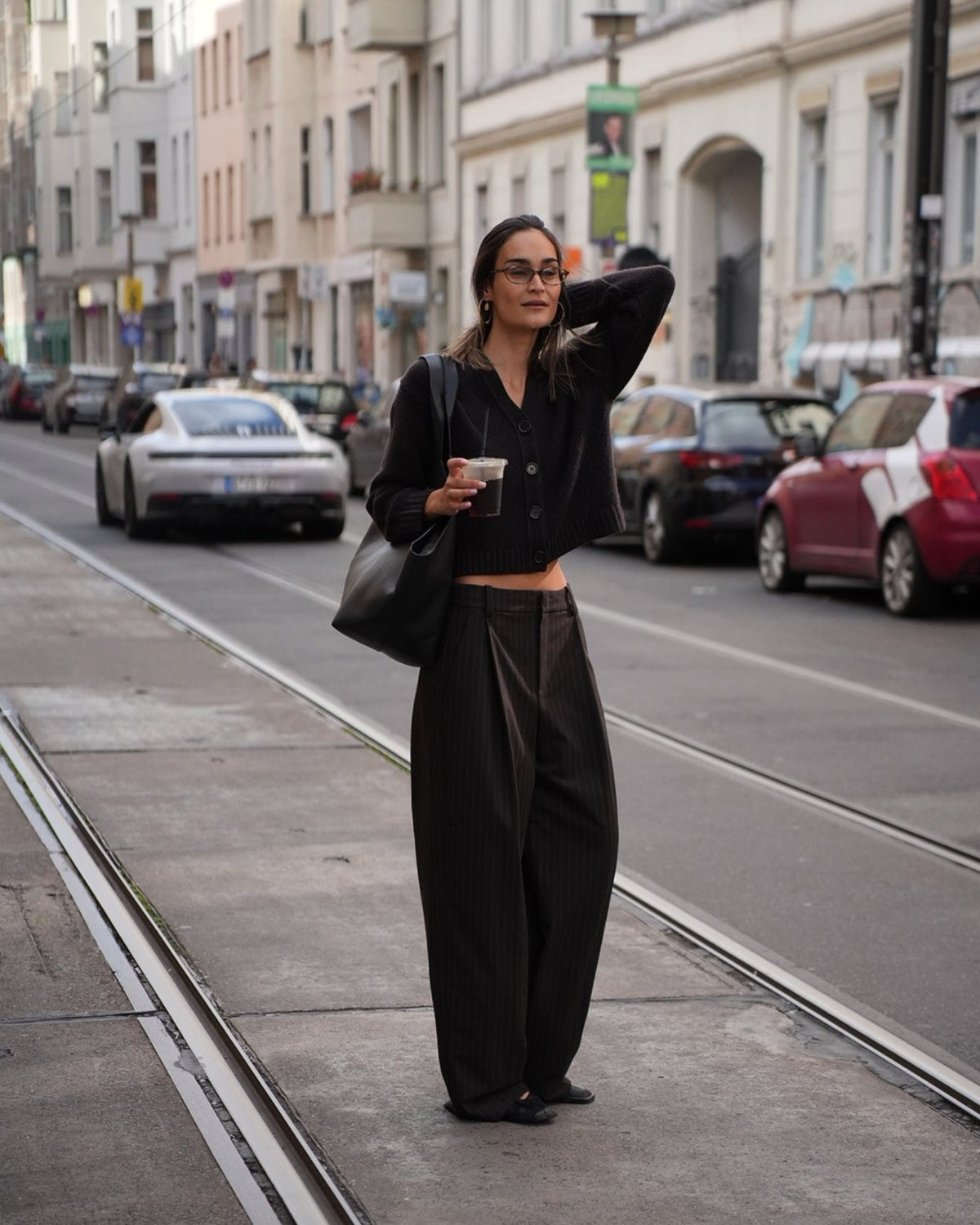 Model wearing a brown cardigan and brown-grey striped wide-leg pants by Vince, full-length front view.